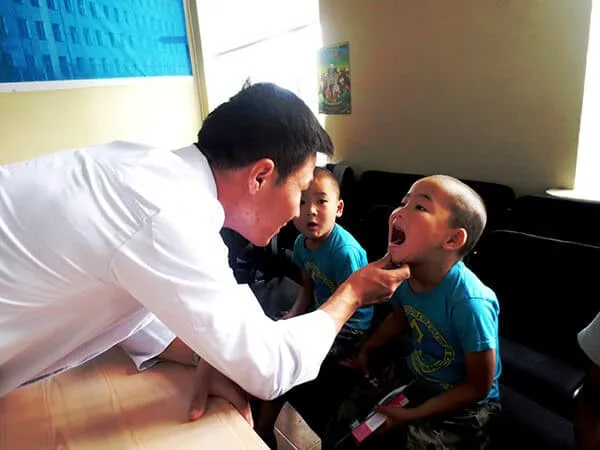 A child receives a dental check from a CNCF health worker